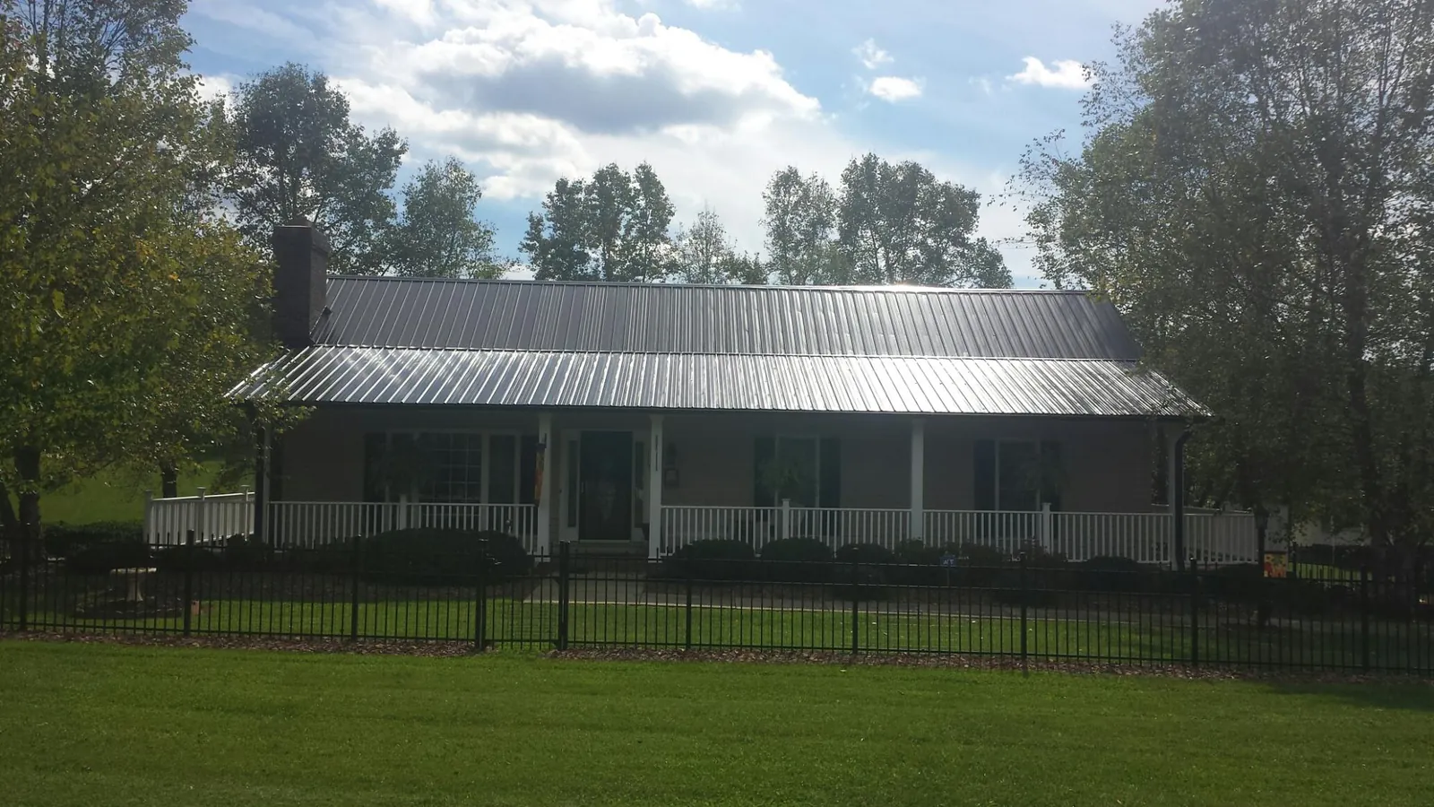 Gray metal roof on a brick ranch with a full width front porch — Gutter Guard Installation work by our crew in Washburn